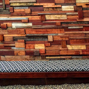 Reclaimed timber feature wall with varied wood tones and geometric patterned outdoor bench seating in Brighton East courtyard