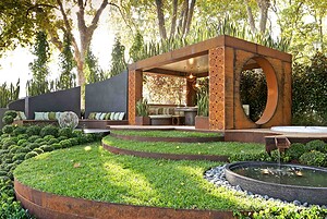 Modern outdoor pavilion with circular timber cutout, sculptural concrete walls and terraced lawn levels in Melbourne