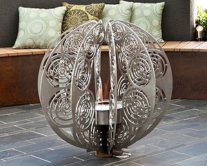 Sculptural steel sphere water feature with intricate cut patterns in contemporary courtyard