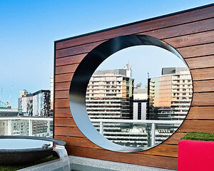 Large circular opening in horizontal timber screen wall frames Melbourne Docklands cityscape views from modern rooftop garden