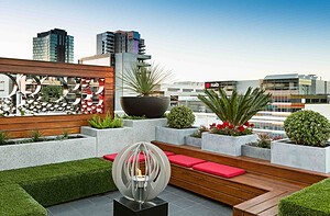 Modern rooftop garden with timber decking, built-in seating, concrete planters and city views in Docklands Melbourne