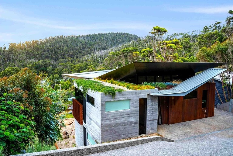 Modern home with native grass green roof and corten steel terracing set into coastal bushland at Separation Creek