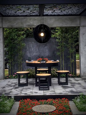 Modern concrete pavilion with round timber dining table and black pendant light, Mandala Moon Gate Garden Nagasaki