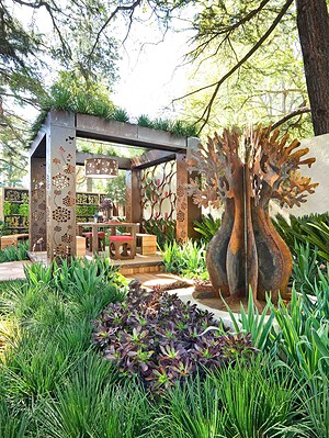 Prefabricated outdoor pavilion with decorative corten steel panels and sculptural tree artwork at Melbourne show garden