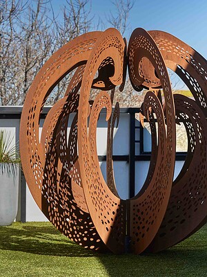 Large perforated corten steel sculptural element on artificial turf rooftop terrace with city views, St Kilda