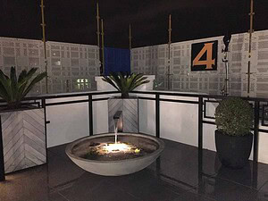 Circular water feature with central fountain illuminated at night on St Kilda rooftop terrace with black railings