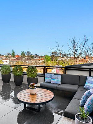 Modern rooftop terrace with grey modular seating, wooden coffee table and city views in St Kilda