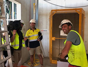 Construction workers in high-vis gear and hard hats meeting during The Block rooftop terrace build in St Kilda