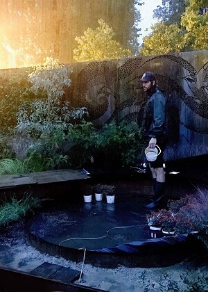 Person tending fire feature at dusk in award-winning Garden of the Little Wattlebird, Nagasaki, Japan