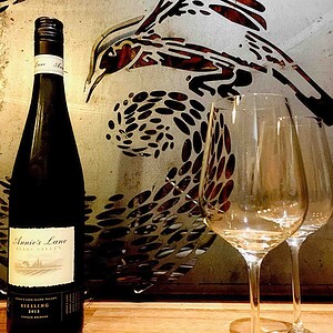 Wine bottle and glasses displayed against decorative wall art featuring bird motifs in award-winning Nagasaki garden