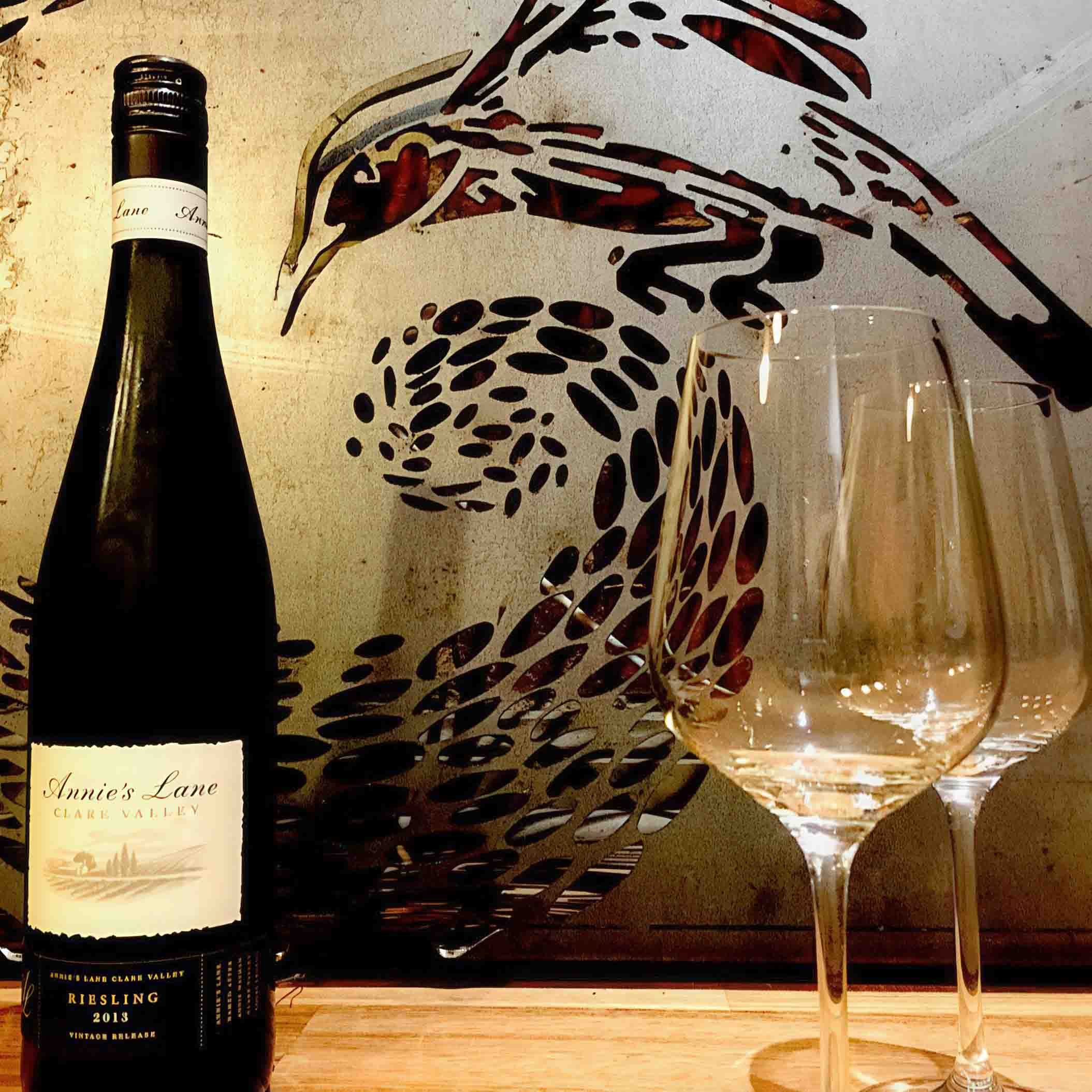 Wine bottle and glasses displayed against decorative wall art featuring bird motifs in award-winning Nagasaki garden
