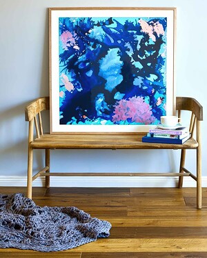 Wooden bench with abstract blue and pink artwork displayed above, styled with books and knitted throw in interior setting