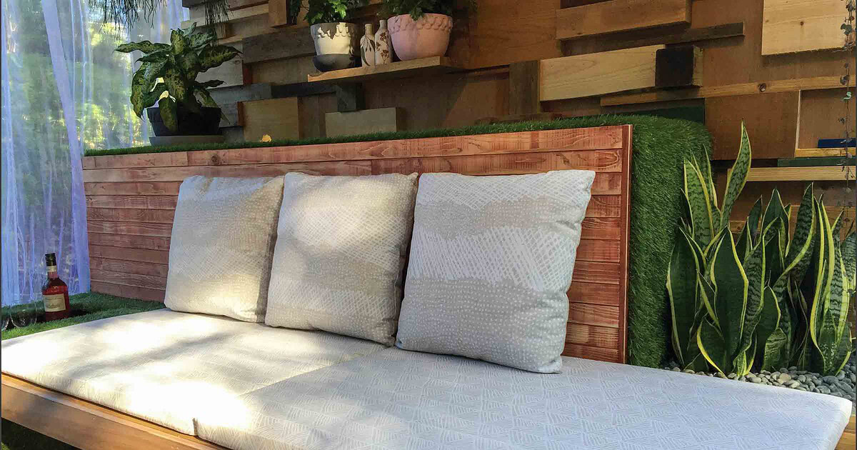 Built-in timber daybed with white cushions on compact balcony garden in Melbourne with vertical timber screening