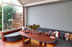 Built-in curved seating with blackbutt timber table around fire pit in covered outdoor dining area, Armstrong Street Ballarat