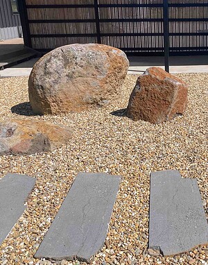 Large basalt boulders positioned in gravel garden with concrete stepping stones and bamboo screening, Gisborne