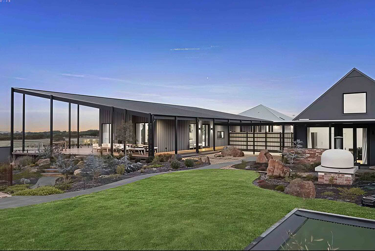 Modern single-story home with curved exposed aggregate paths connecting deck to pool area in Gisborne country garden
