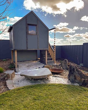 Timber cubby house on stilts with fire pit and natural stone landscaping in Gisborne Macedon Ranges garden
