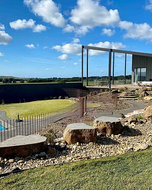 Curved exposed aggregate paths connecting modern deck to pool area with native plantings in Gisborne Macedon Ranges garden