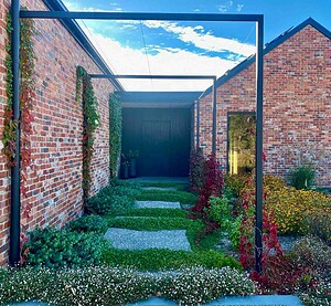 Steel frame arbour entrance with Virginia creeper vines leading to dark timber door at Mount Buninyong country estate