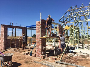 Construction workers building timber roof frame and brick walls at Mount Buninyong country estate construction site