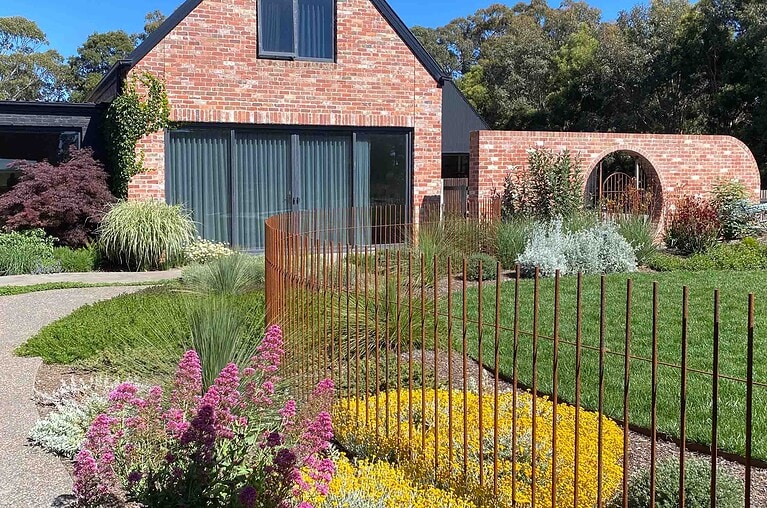 Custom steel rod pool fence with vertical bars creating safety barrier around garden beds in Mount Buninyong country estate